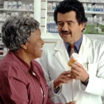 Pharmacist explaining a pantoprazole prescription and ways to save to a patient at the pharmacy counter