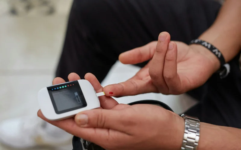 Man checking his blood glucose level with a meter at home